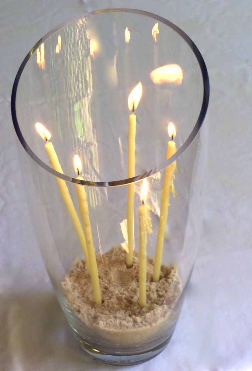 a glass vase of lit candles in a wedding ceremony
